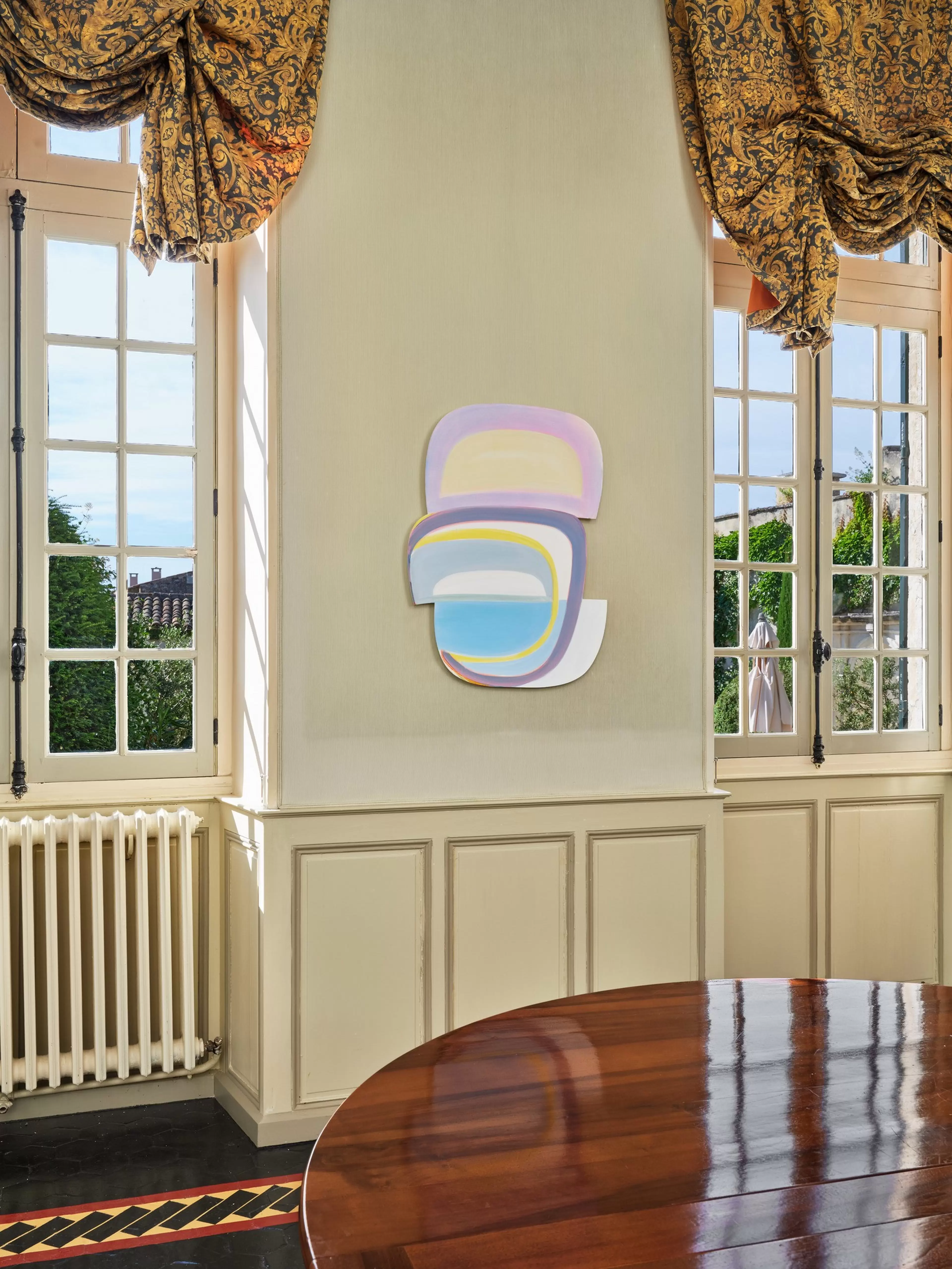Shaped canvas painting of stacked, rounded panels in soft pastel yellow, lavender and blue, outlined with thin curving lines.